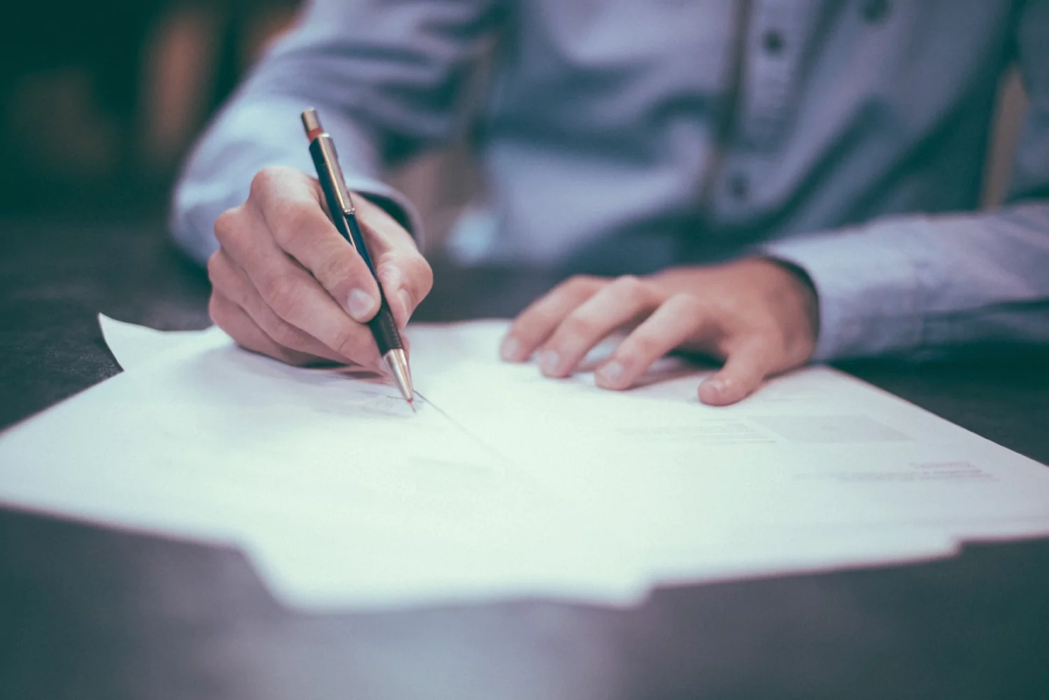 a pastor sitting at a desk and working through insurance and finance documents, pen in hand