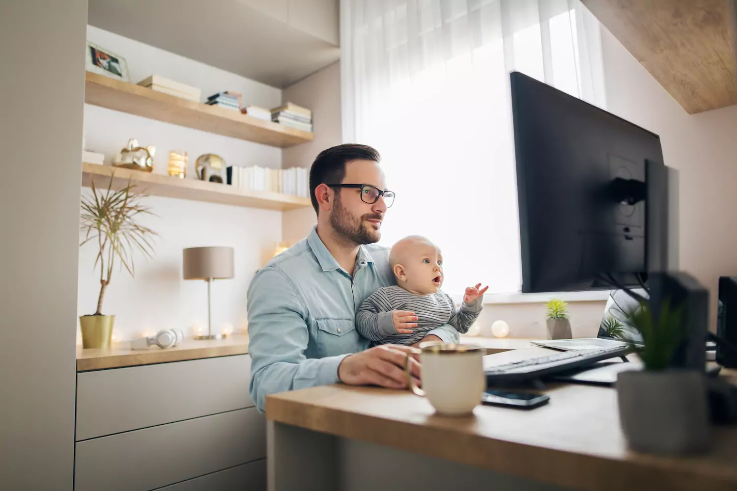 Dad doing work in his office with baby in his lap