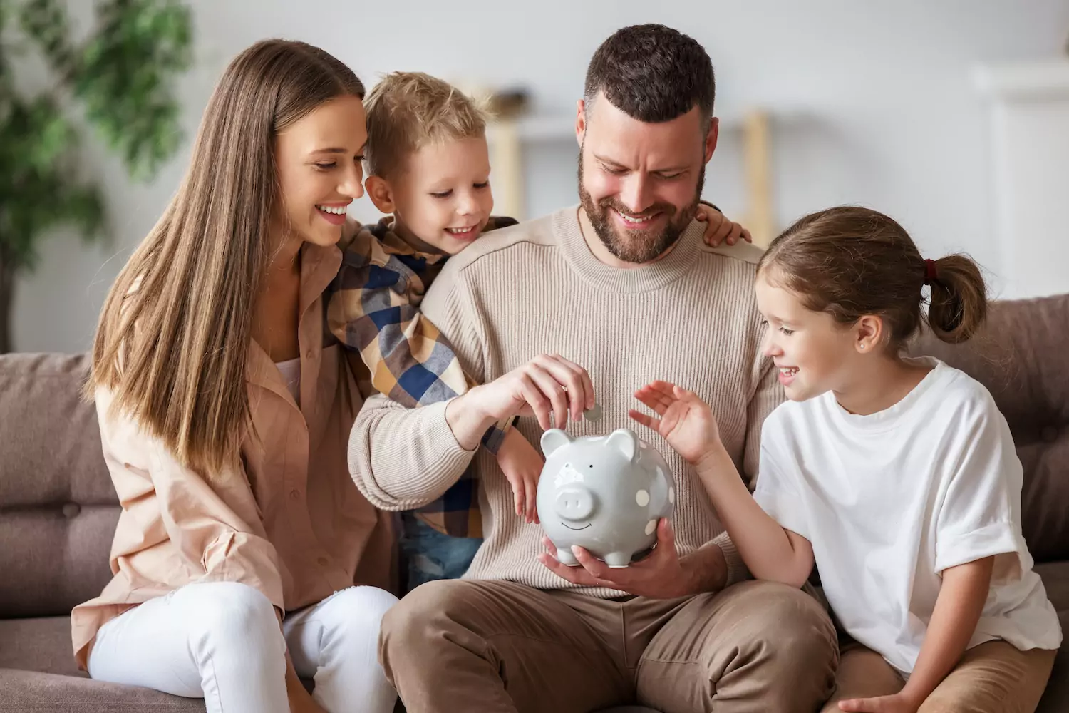 Family of four saving money and putting it in a piggy bank