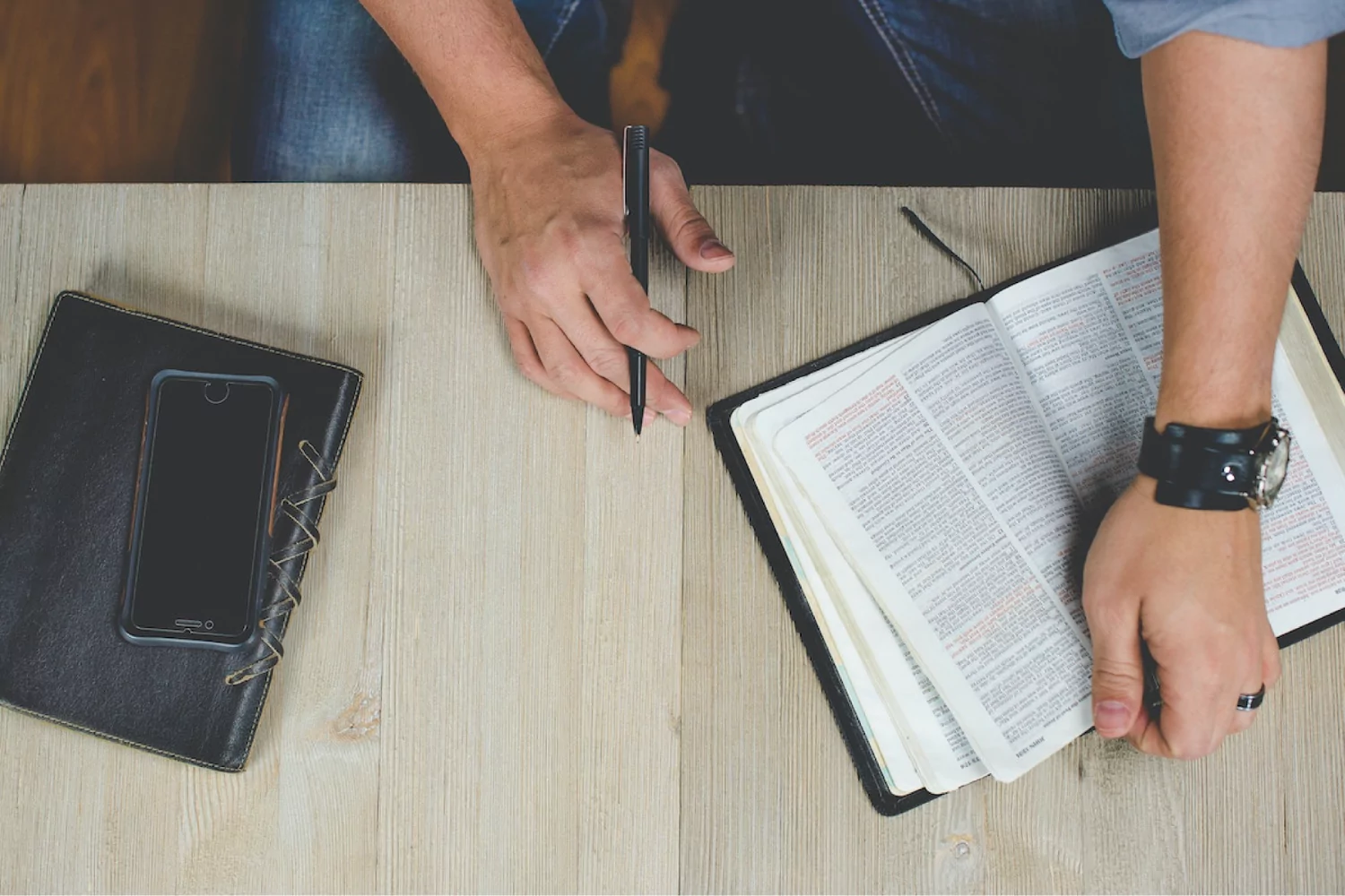 a man studying his Bible at a wooden table