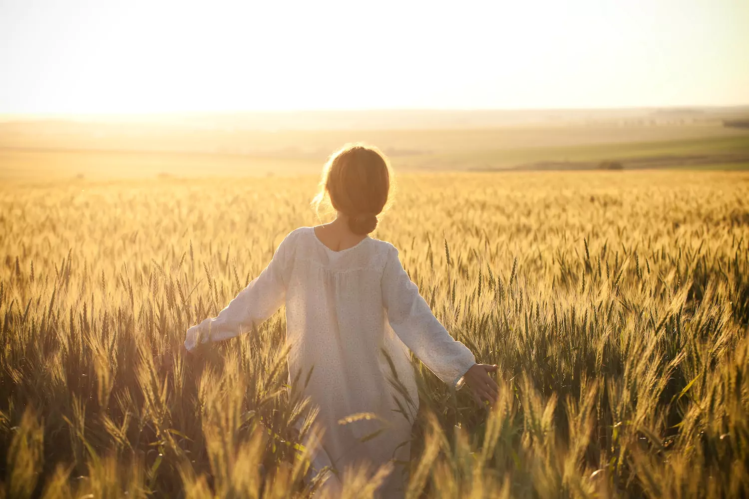 a pastor's daughter struggling with fear walks through a field of wheat at golden hour