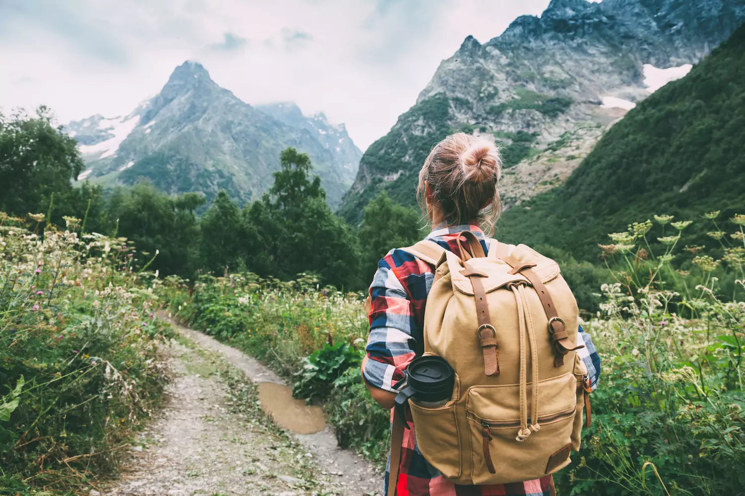 a female overseas missionary carries her backpack on a mountain trail