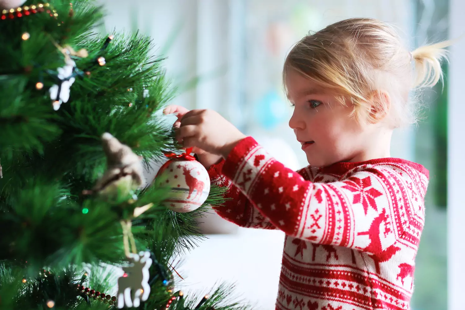 A pastor's daughter celebrates advent, hanging an ornament on the family Christmas tree.